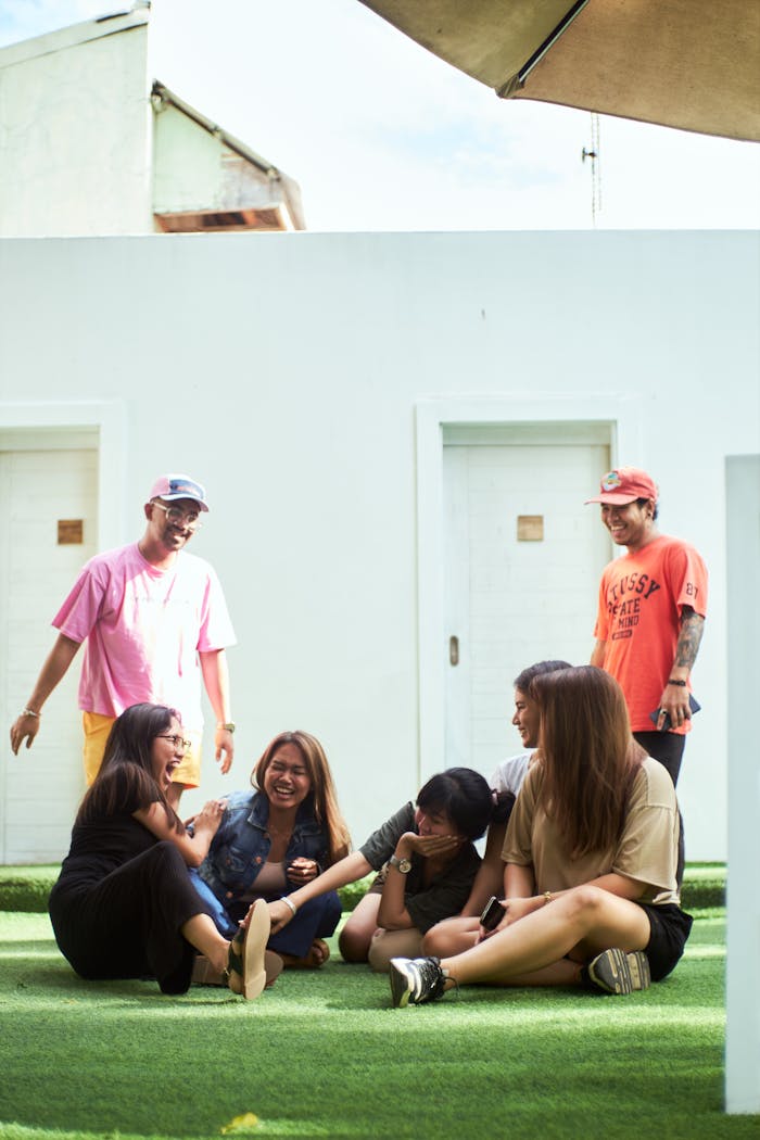 A cheerful group of adults laughing and relaxing outdoors on a sunny day.