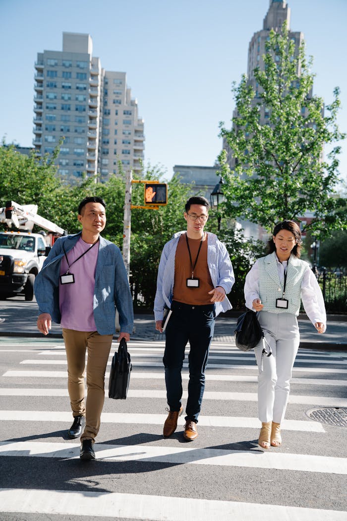 Three professionals crossing a busy urban street on a sunny day, showcasing teamwork and diversity.